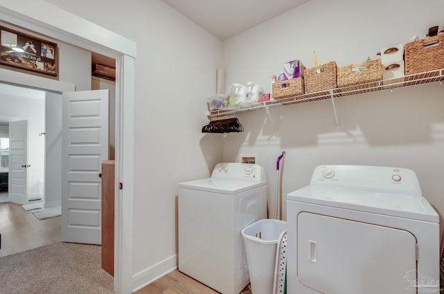 laundry area featuring baseboards, laundry area, light wood finished floors, and washer and clothes dryer