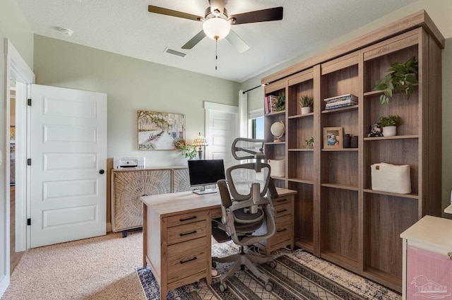 home office featuring a ceiling fan, visible vents, and light carpet