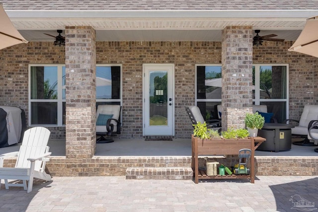 doorway to property featuring a ceiling fan, a patio, and a shingled roof
