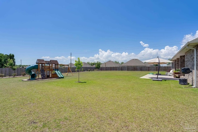 view of yard featuring a playground, a fenced backyard, and a patio area
