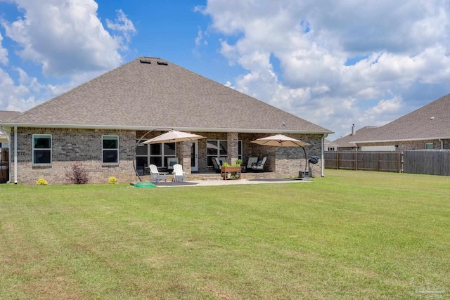 rear view of property featuring a lawn, a patio, fence, and brick siding