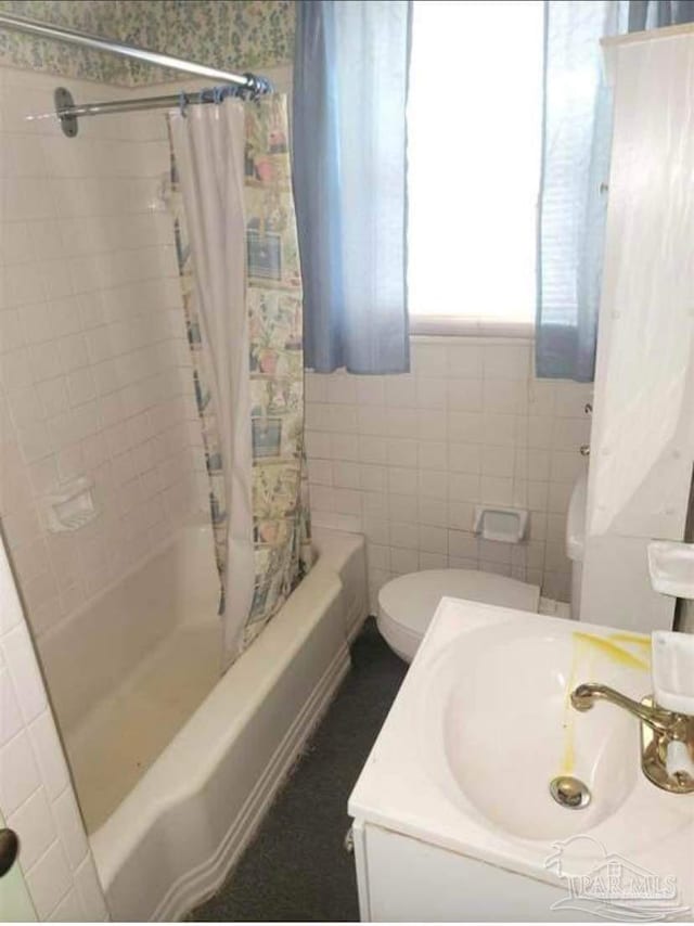 bathroom featuring a sink, toilet, tile walls, and shower / bath combination with curtain