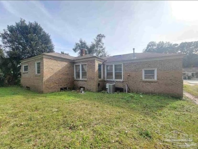 rear view of house with a yard, brick siding, and central AC