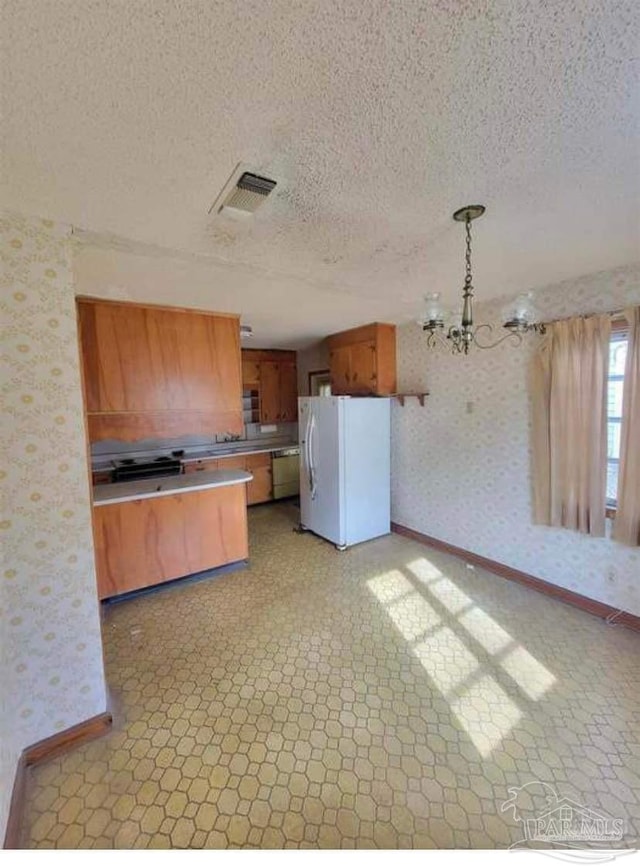 kitchen featuring visible vents, light floors, freestanding refrigerator, and wallpapered walls