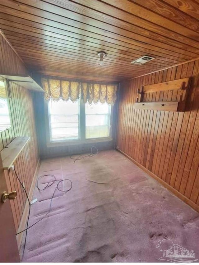 empty room featuring visible vents, wood walls, and wooden ceiling