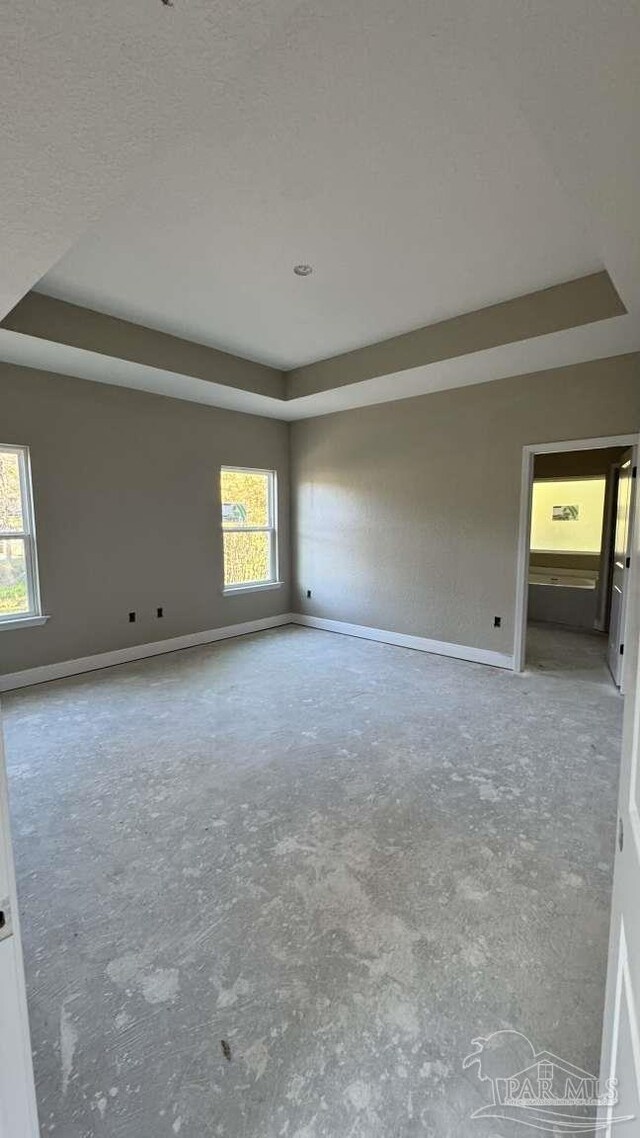 empty room featuring a raised ceiling and baseboards