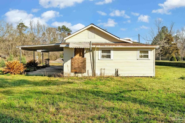 back of property with a carport and a yard