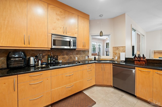 kitchen with pendant lighting, sink, tasteful backsplash, stainless steel appliances, and dark stone countertops