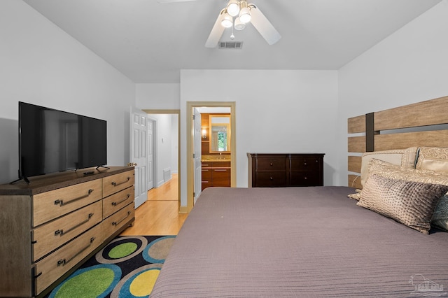 bedroom featuring ceiling fan, light hardwood / wood-style flooring, and connected bathroom