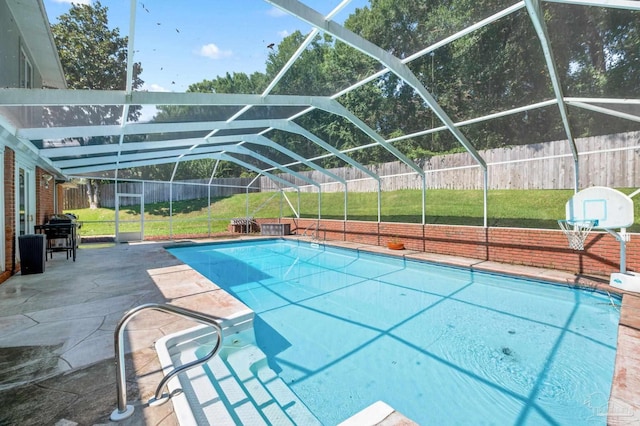 view of swimming pool with glass enclosure, a patio area, and a lawn