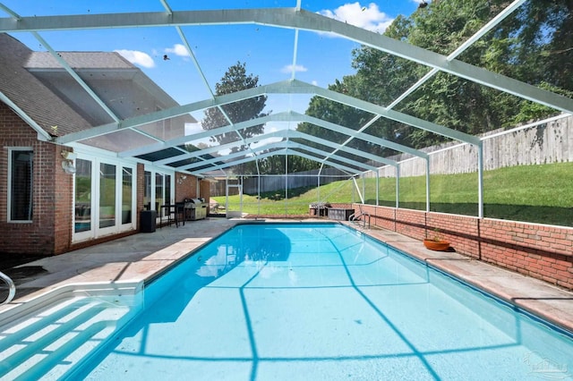 view of pool featuring a patio, glass enclosure, and a yard