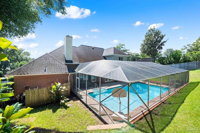 view of swimming pool with a lawn and a lanai