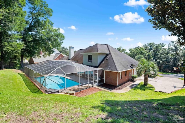 back of property with glass enclosure, a patio area, and a yard