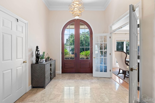 foyer entrance featuring ornamental molding, an inviting chandelier, and french doors