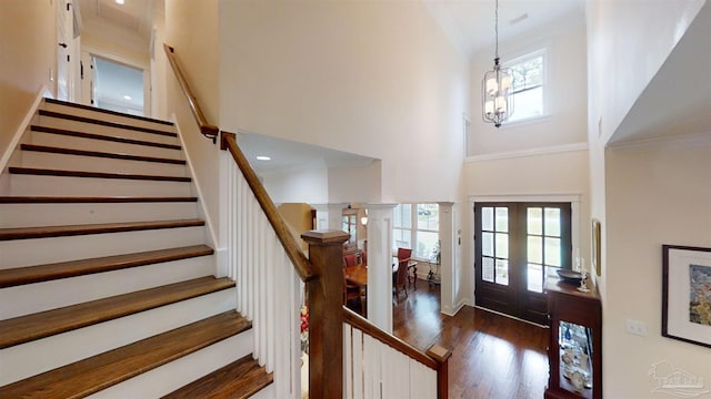 entryway featuring dark wood-type flooring, french doors, an inviting chandelier, high vaulted ceiling, and ornamental molding