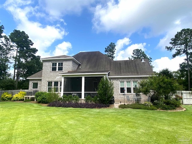 rear view of house with a yard and a sunroom