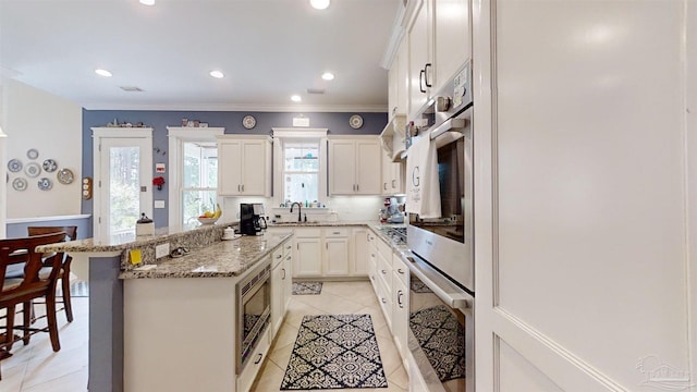 kitchen featuring a kitchen island, white cabinetry, sink, a kitchen breakfast bar, and stainless steel appliances