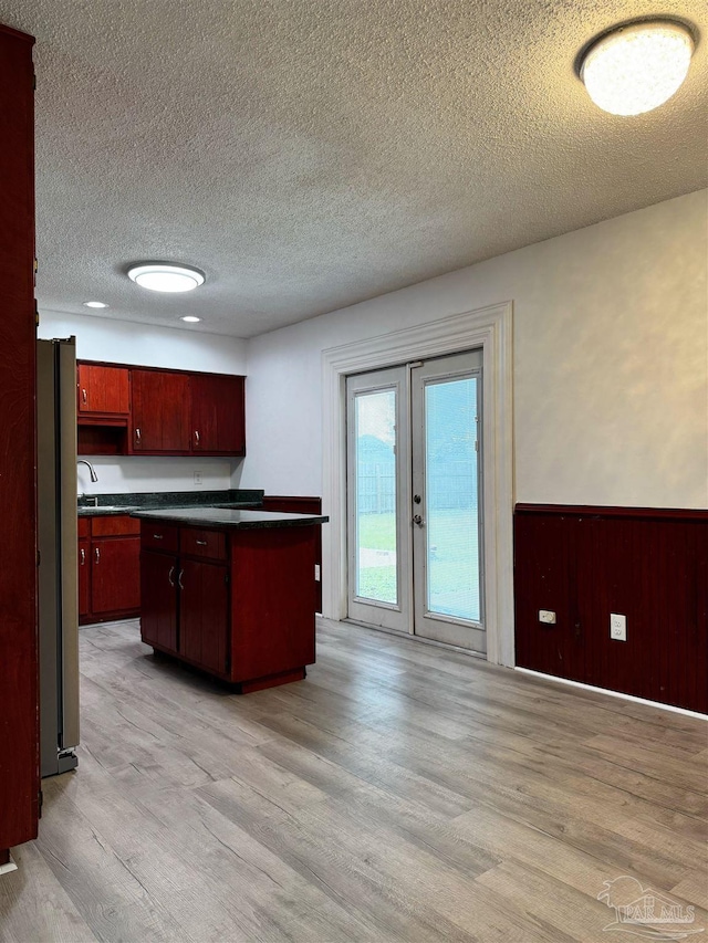 kitchen with fridge, french doors, dark countertops, and light wood finished floors