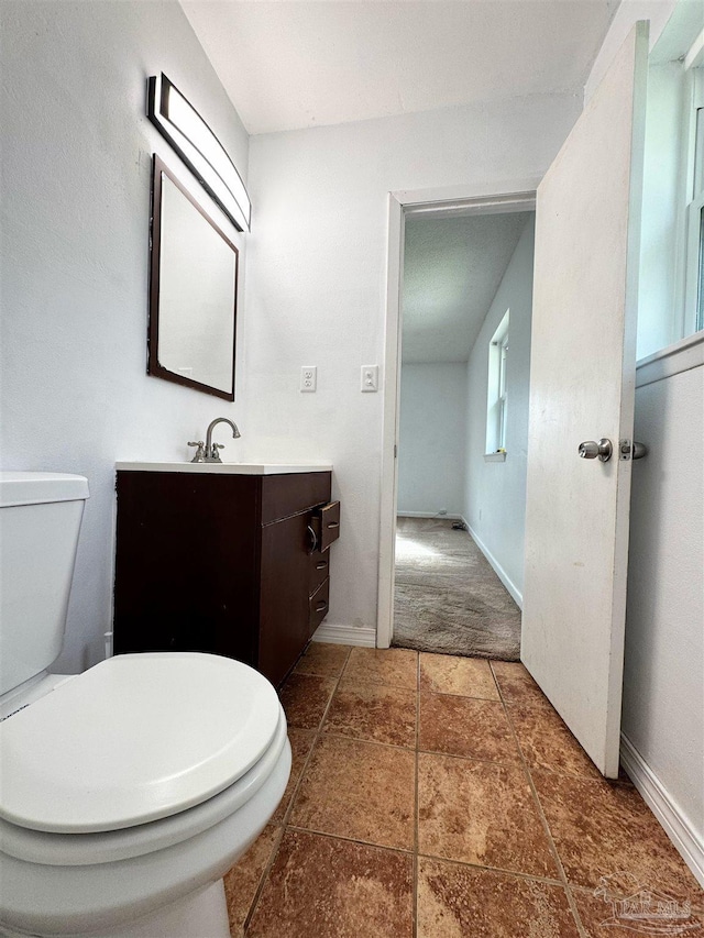 half bathroom with vanity, tile patterned floors, toilet, and baseboards