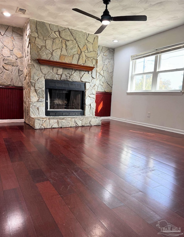 unfurnished living room with visible vents, wood-type flooring, a fireplace, baseboards, and ceiling fan