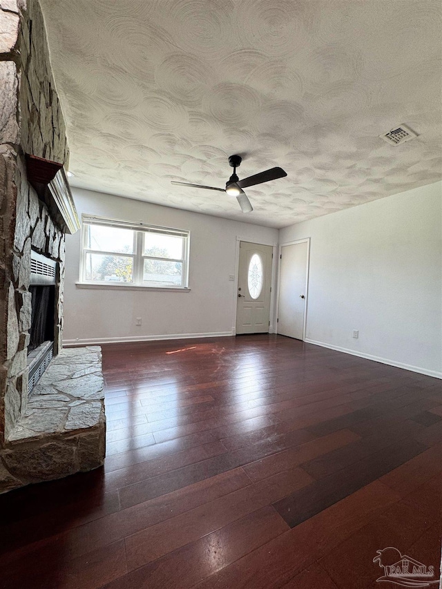 unfurnished living room featuring visible vents, ceiling fan, a fireplace, a textured ceiling, and wood-type flooring