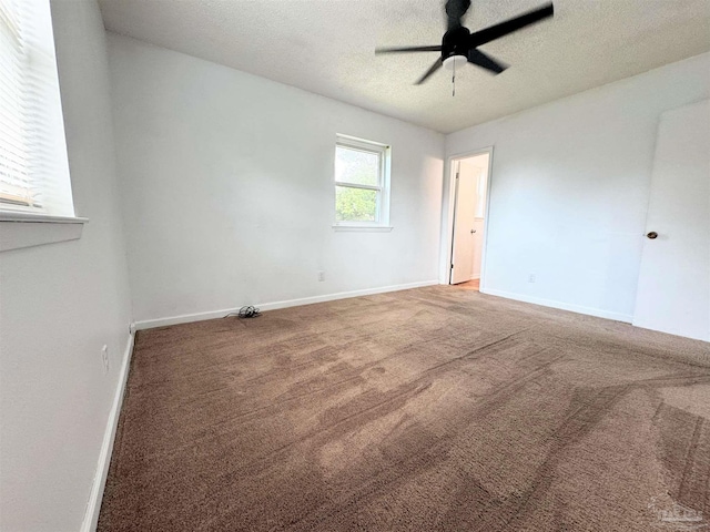 carpeted spare room featuring baseboards, a textured ceiling, and a ceiling fan