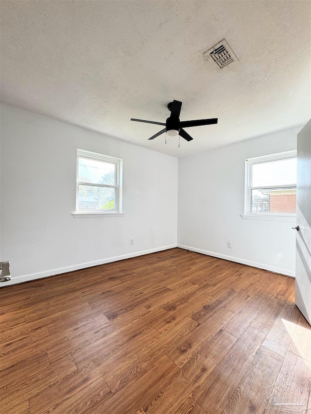 unfurnished room featuring ceiling fan, visible vents, baseboards, and wood finished floors