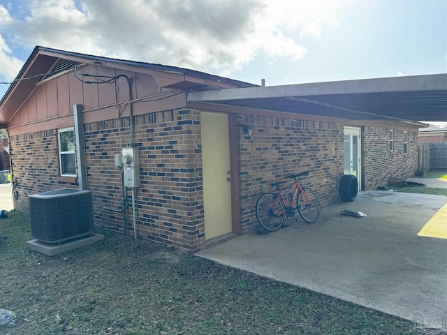 view of side of home with a carport, central air condition unit, and brick siding