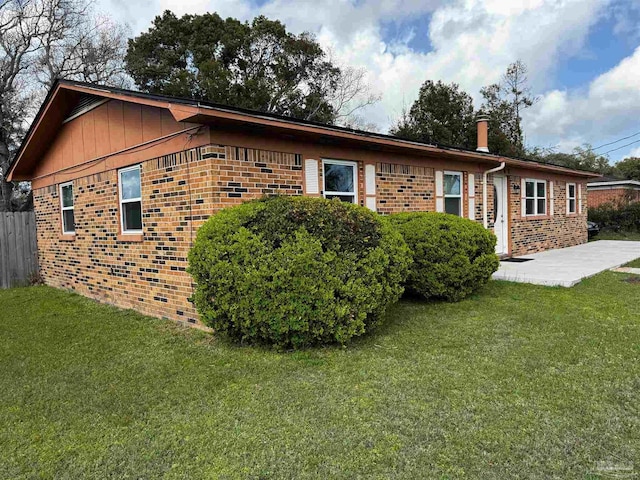 rear view of property featuring brick siding, a patio, a yard, and fence