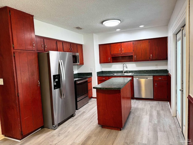 kitchen featuring dark countertops, visible vents, light wood-type flooring, appliances with stainless steel finishes, and a sink