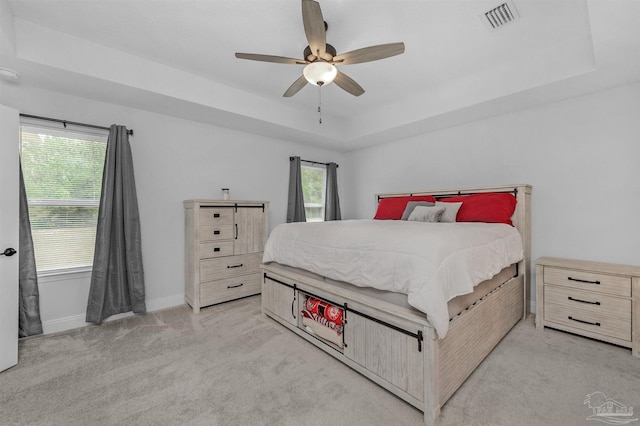 bedroom with a tray ceiling, ceiling fan, and light colored carpet