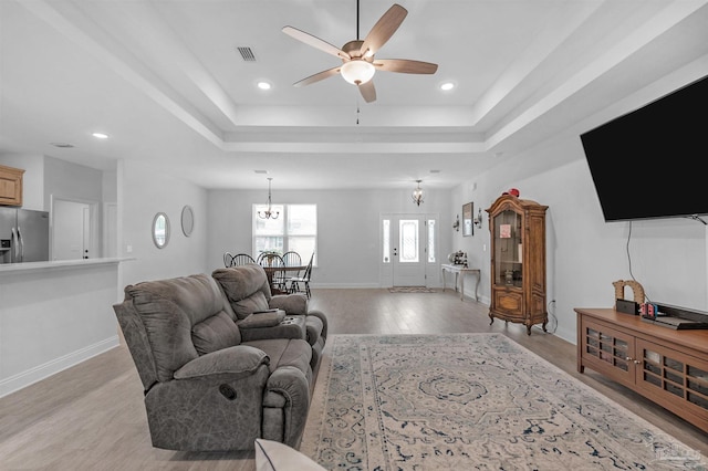 living room with ceiling fan, light hardwood / wood-style floors, and a tray ceiling