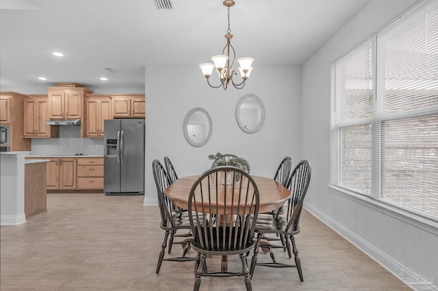 dining area with light hardwood / wood-style flooring and an inviting chandelier