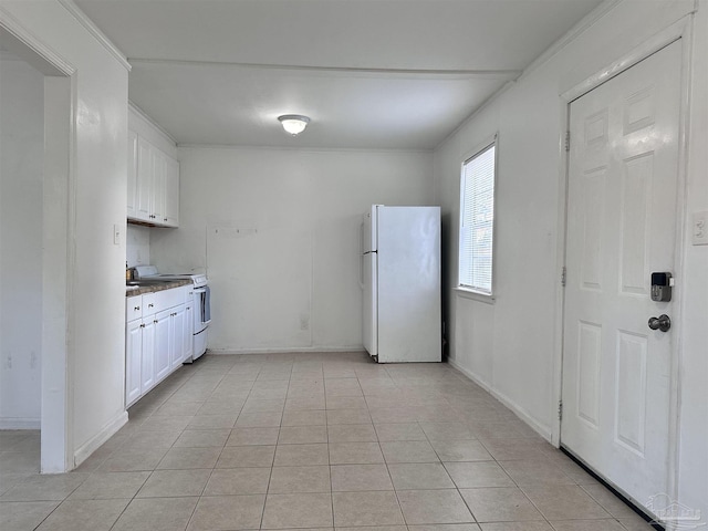 kitchen with light tile patterned floors, white appliances, baseboards, and white cabinets