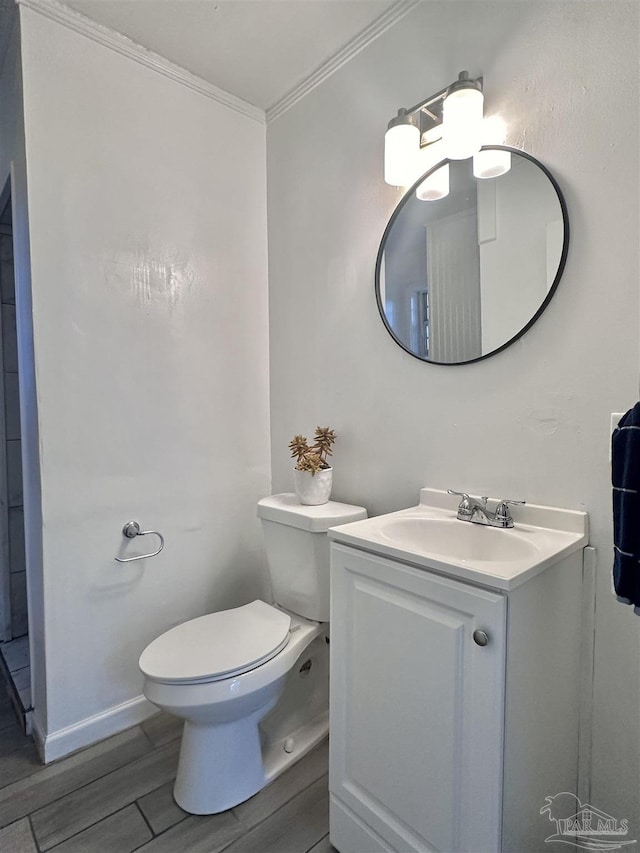 half bath featuring ornamental molding, vanity, toilet, and wood tiled floor