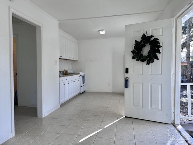 kitchen with white electric stove, light tile patterned floors, white cabinetry, baseboards, and ornamental molding