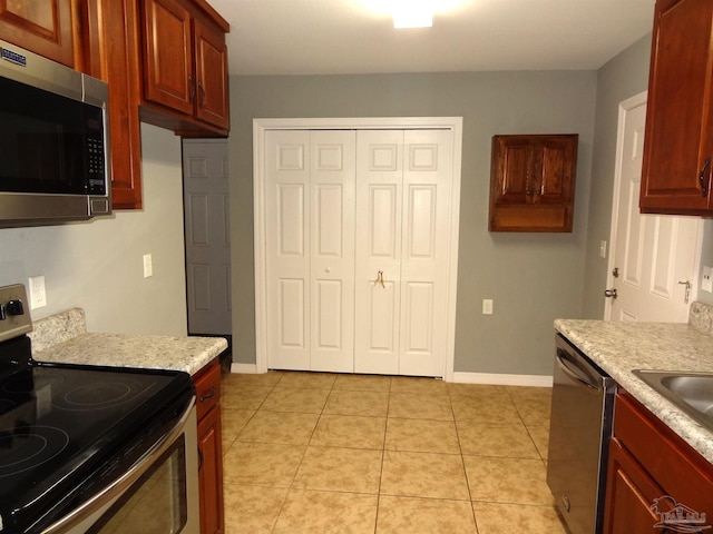 kitchen featuring light tile patterned floors, light stone counters, and stainless steel appliances