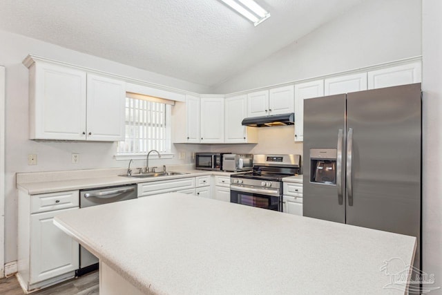 kitchen featuring sink, appliances with stainless steel finishes, white cabinetry, vaulted ceiling, and light wood-type flooring