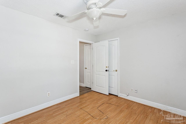 unfurnished room featuring ceiling fan, wood-type flooring, and a textured ceiling