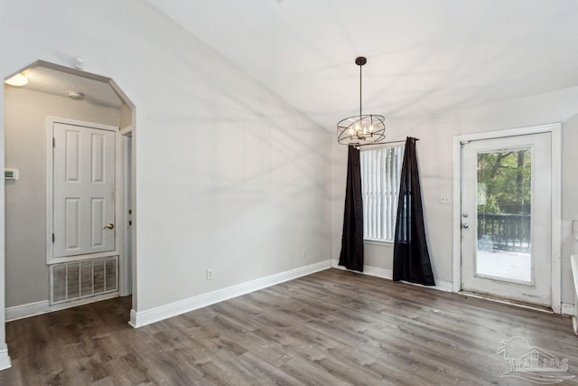 spare room featuring lofted ceiling, a notable chandelier, and hardwood / wood-style flooring