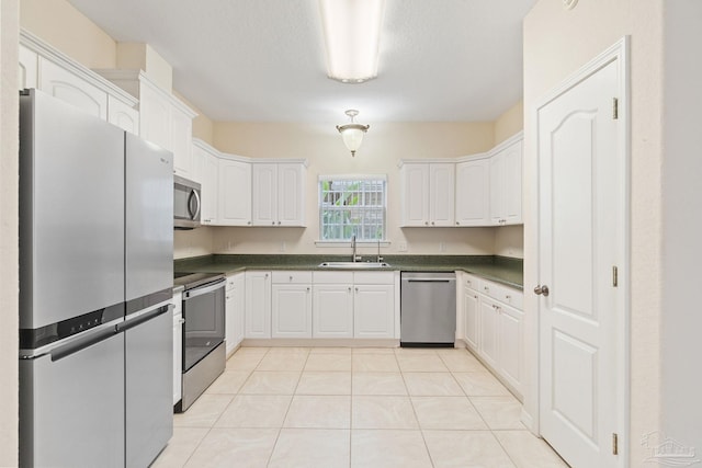 kitchen featuring light tile patterned flooring, sink, white cabinets, stainless steel appliances, and a textured ceiling