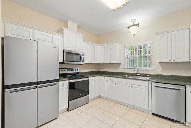 kitchen with stainless steel appliances, white cabinetry, sink, and light tile patterned floors