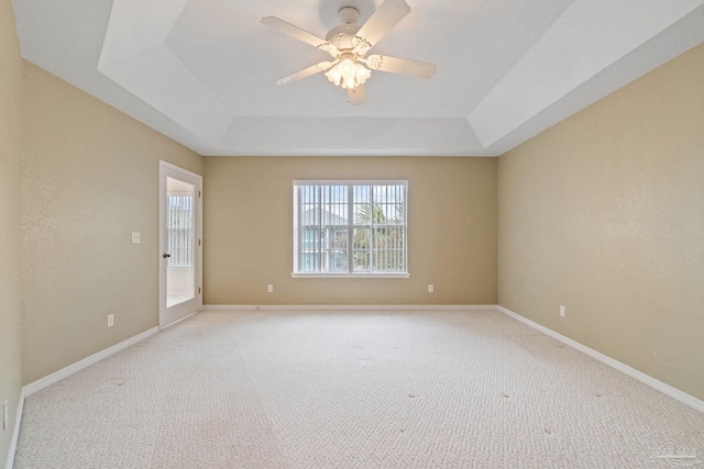 carpeted spare room featuring a raised ceiling and ceiling fan