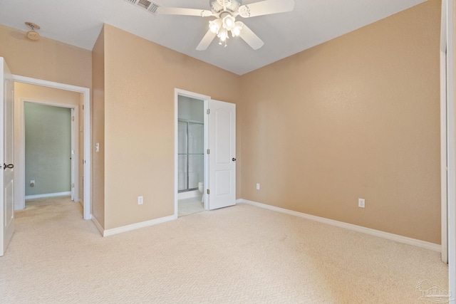 unfurnished bedroom featuring ensuite bath, light colored carpet, and ceiling fan