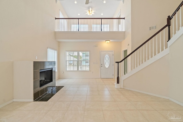 tiled foyer featuring a towering ceiling, a fireplace, and ceiling fan