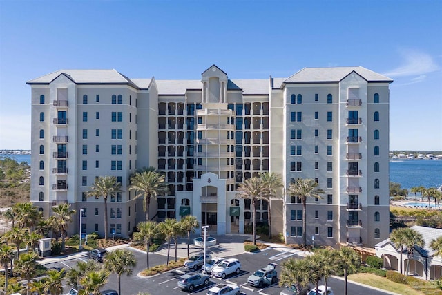 view of building exterior with uncovered parking and a water view