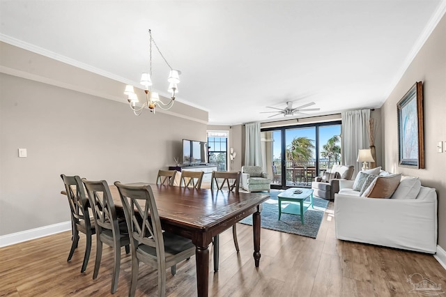 dining space featuring light wood finished floors, ceiling fan with notable chandelier, crown molding, and baseboards