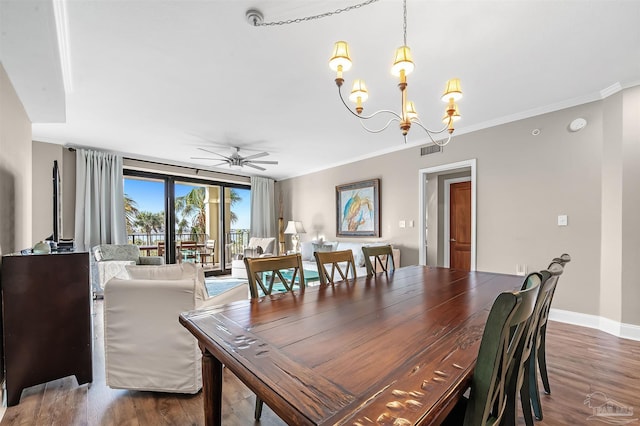 dining space with visible vents, ceiling fan with notable chandelier, wood finished floors, crown molding, and baseboards