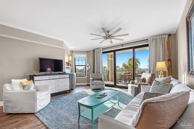 living area featuring a ceiling fan, crown molding, wood finished floors, and baseboards