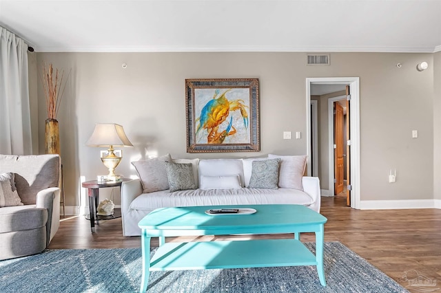 living room with baseboards, wood finished floors, visible vents, and ornamental molding